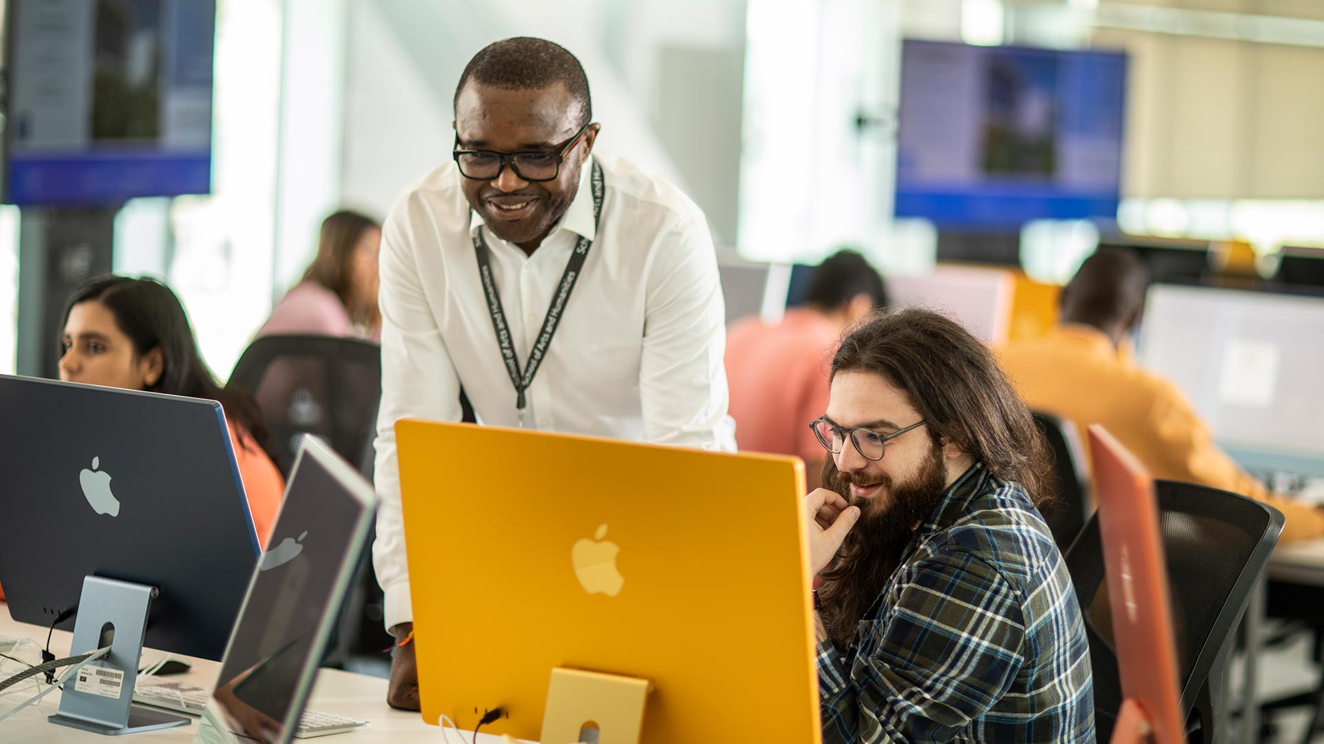 A member of staff helps a student on the new imacs in the Barbara Hepworth Building 