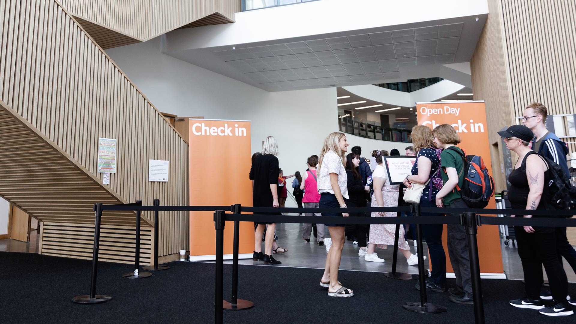 A queue of visitors being greeted by staff to check in to Open Day