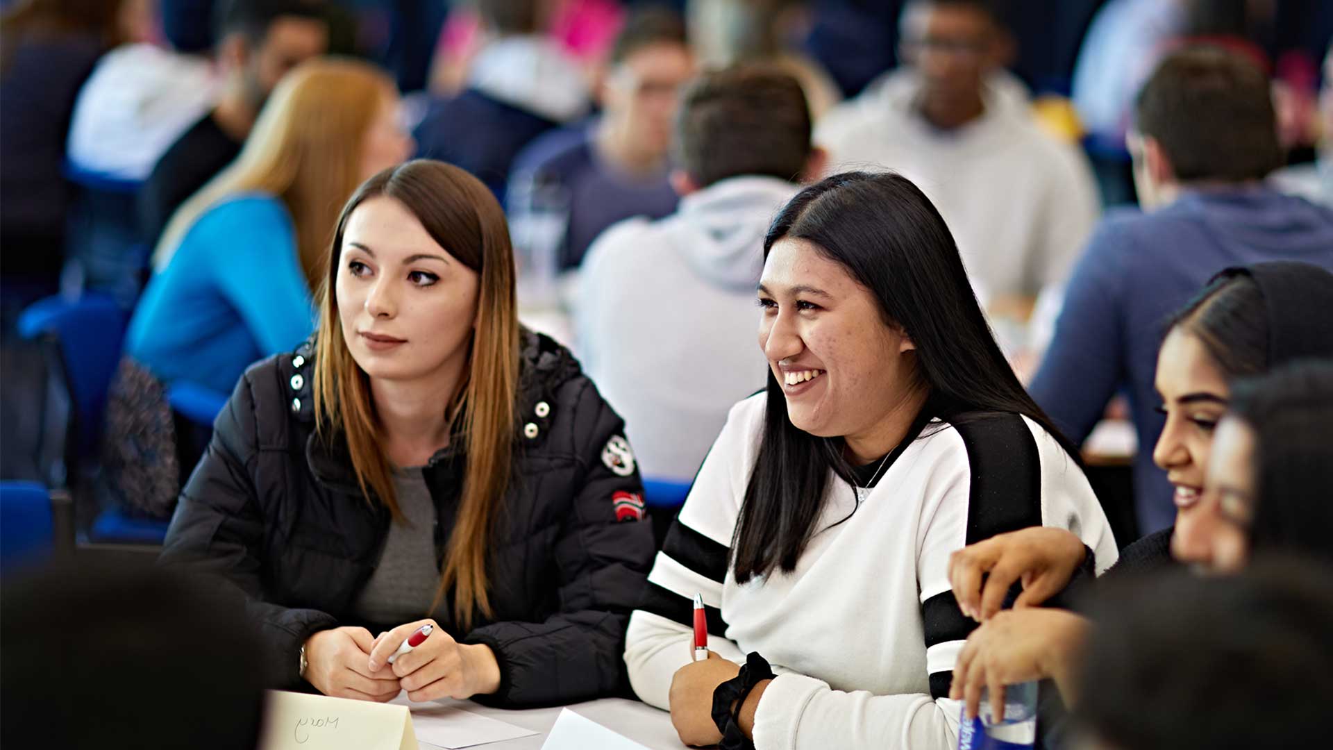 A group of students sat at a table are smiling during the Global Professional Award